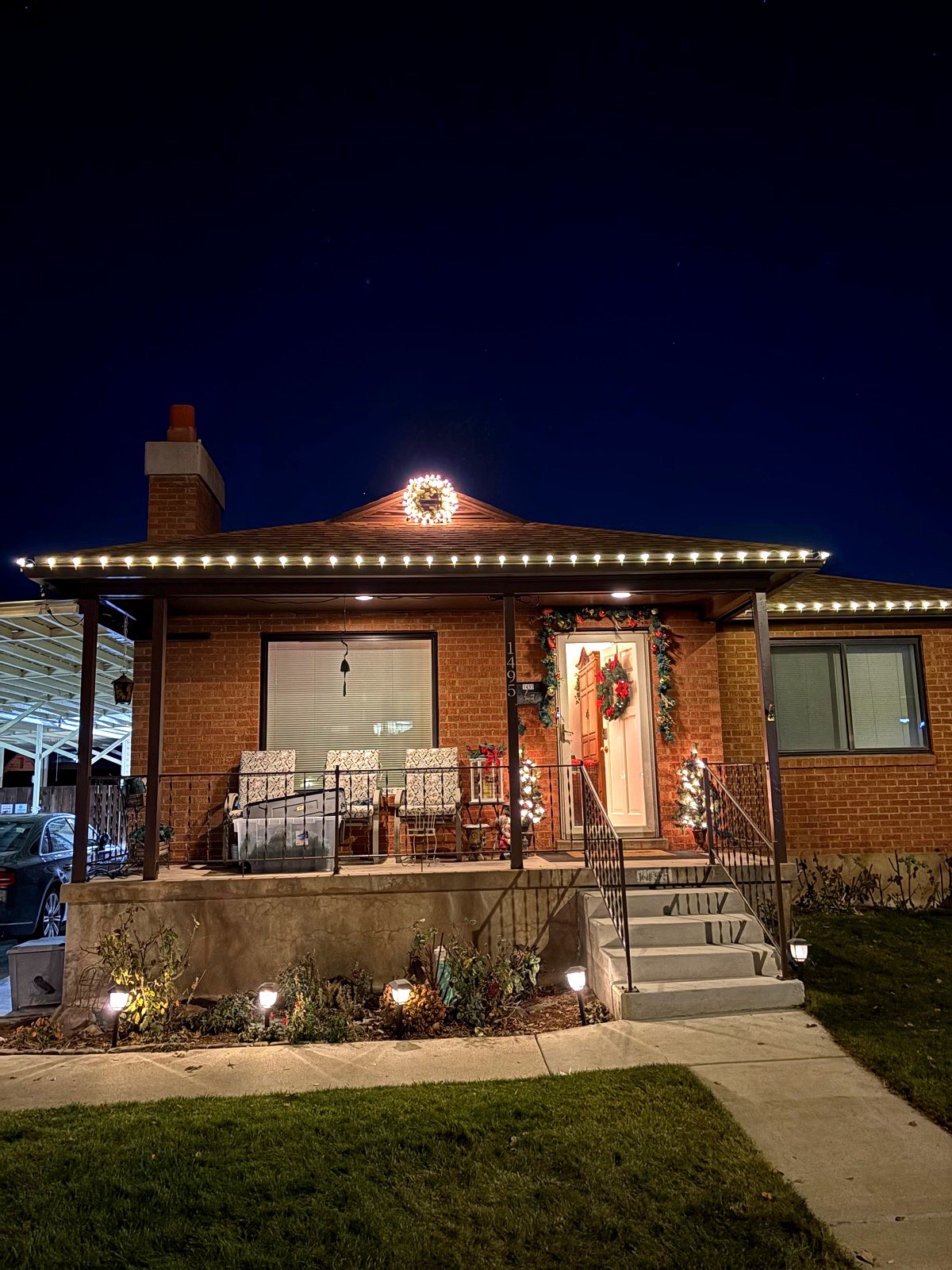 Brick home with warm white roofline lighting, lit wreath and pathway lights